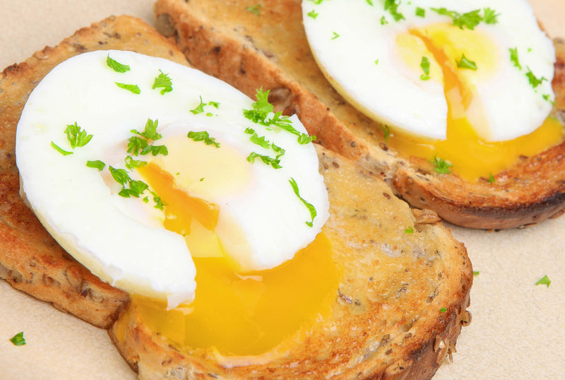 Perfectly poached eggs on toast made with Eggssentials Egg Poacher, topped with herbs.